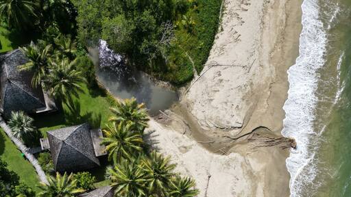 Aerial top view shot of a Poindimie beach river with houses in New Caledonia