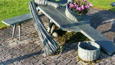 A statue of a man sitting on a bench with a basket of flowers.