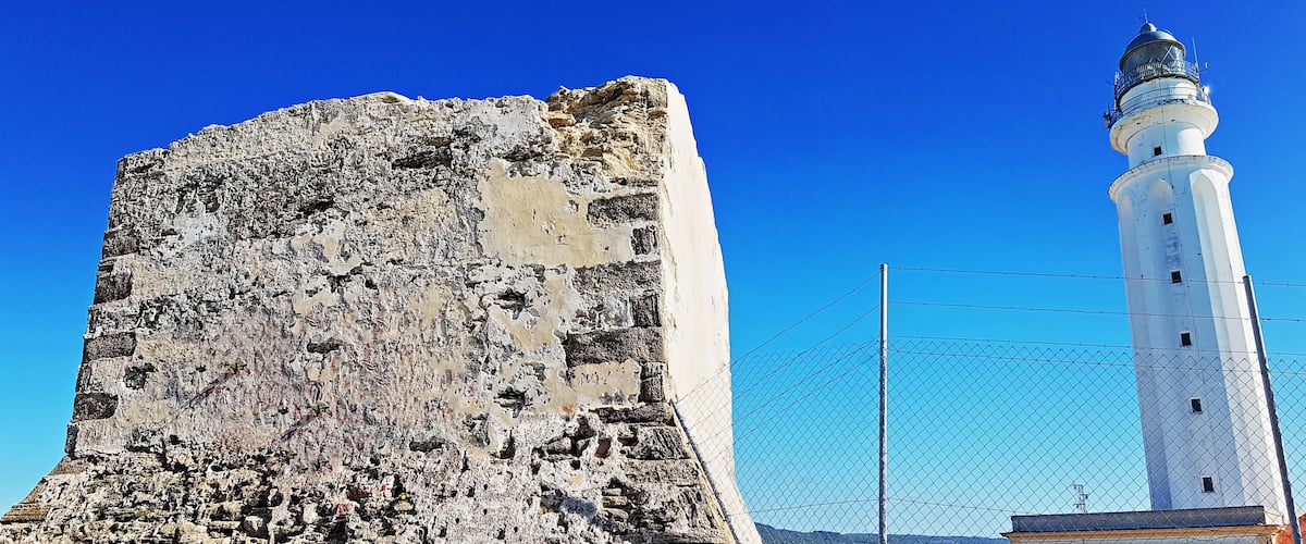 A historic stone tower and a white lighthouse.