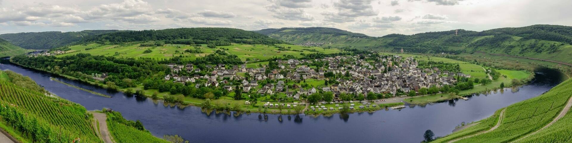 A river winding through a town surrounded by green hills.