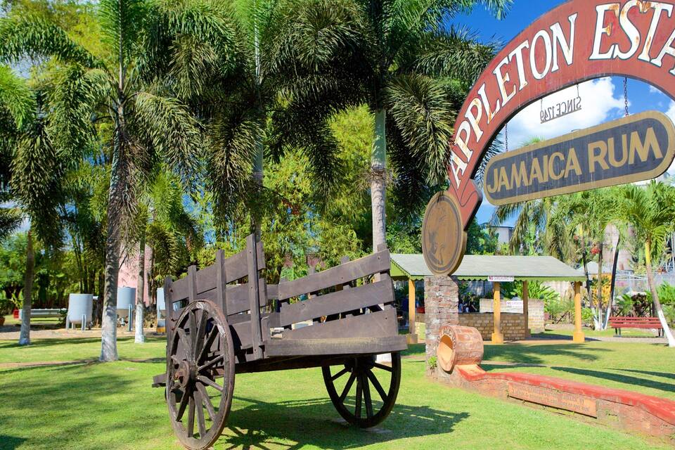 Un cañón de madera, un cartel de Appleton Estate Jamaica Rum y un carro de madera.