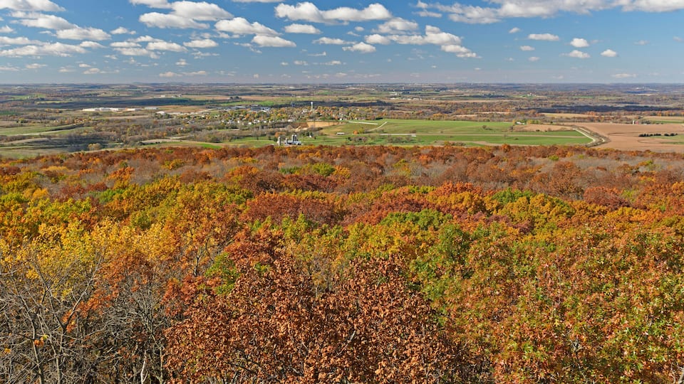 A landscape with autumn foliage, a distant town, and a clear sky.