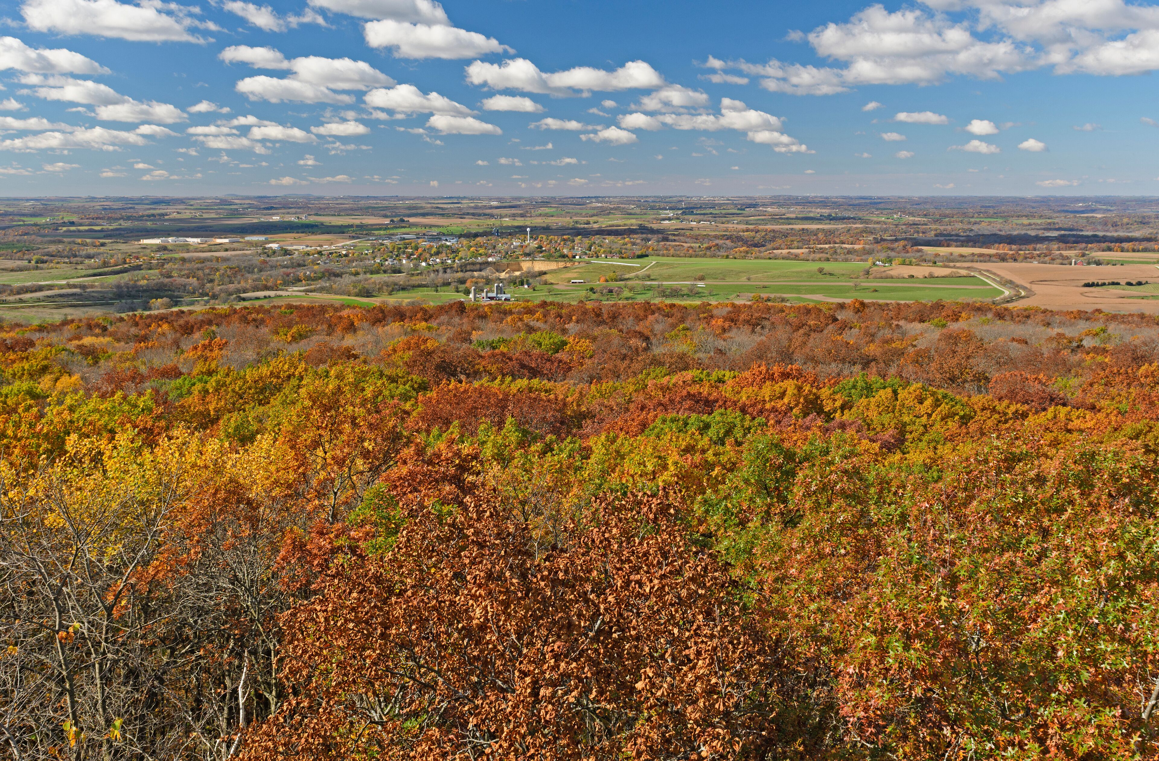 A landscape with autumn foliage, a distant town, and a clear sky.