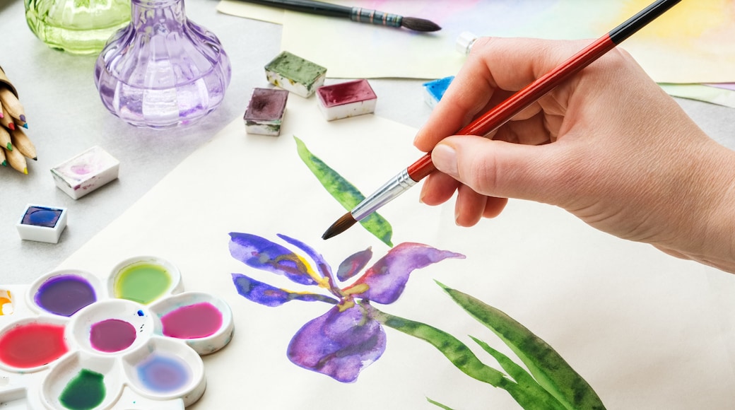Iris flower and artistic equipment on desk. Top view. Painter drawing at working place.