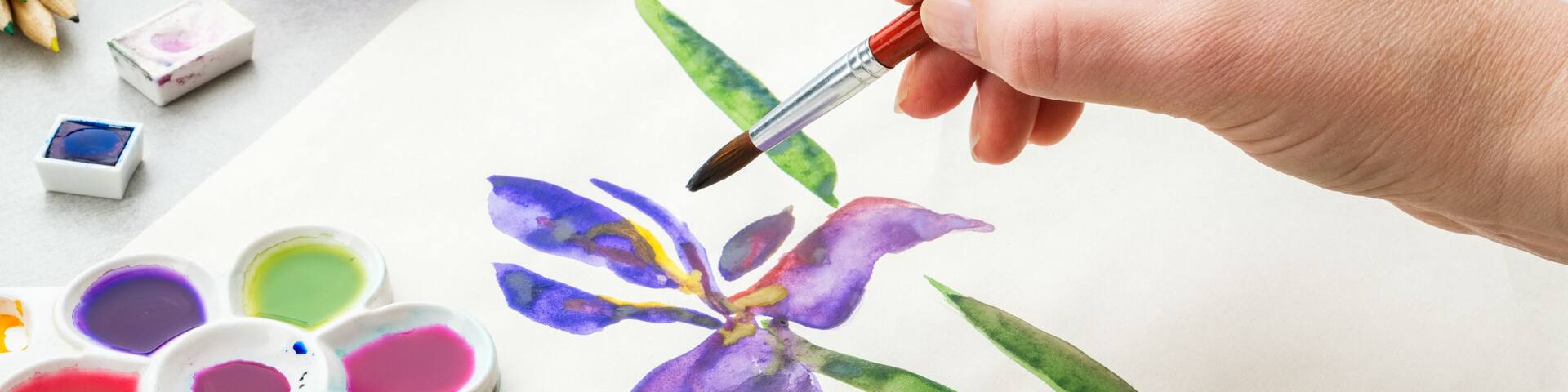 Iris flower and artistic equipment on desk. Top view. Painter drawing at working place.