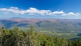 Un paysage montagneux, avec de vastes forêts et un ciel bleu dégagé.