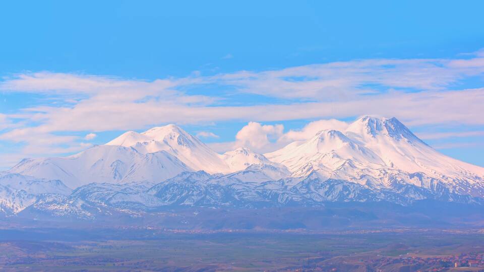 A range of snow-capped mountains with a clear sky above.