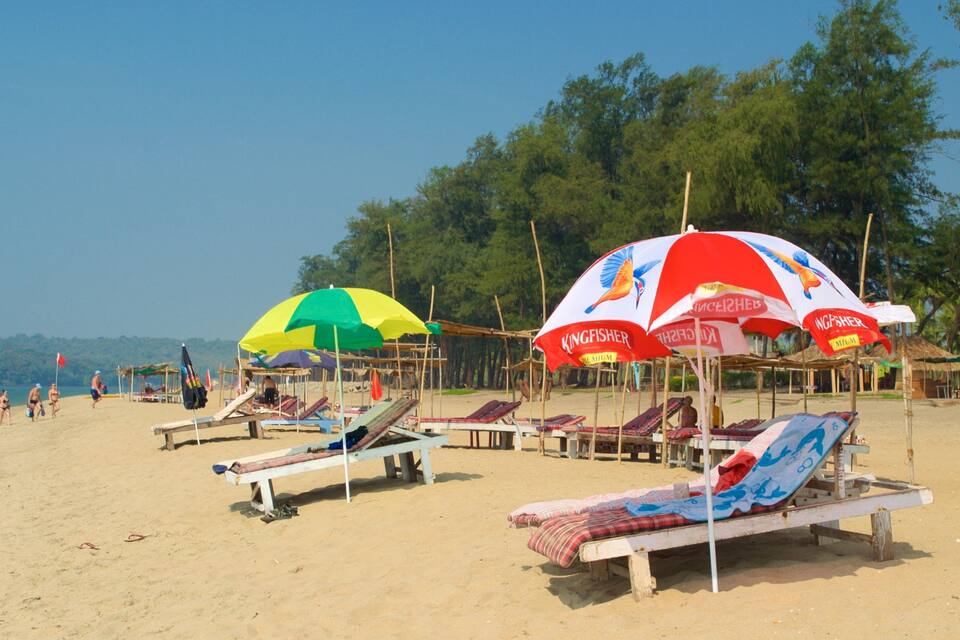 A beach with sun loungers and colorful umbrellas.