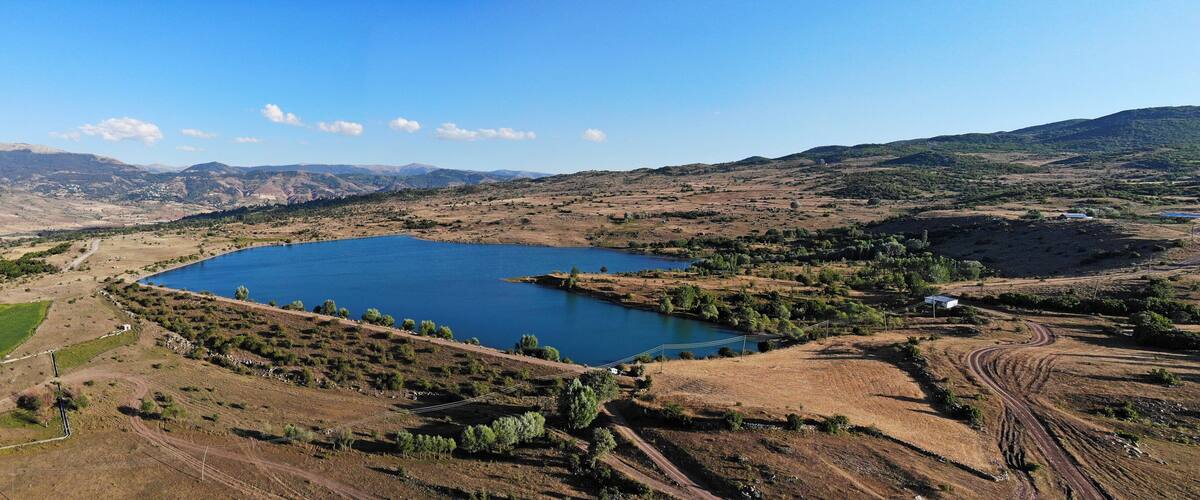A large lake surrounded by hills and sparse vegetation.