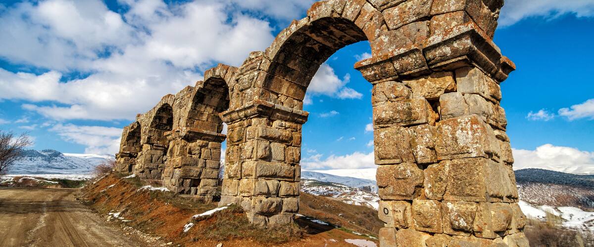 Ancient stone arches in a mountainous landscape.