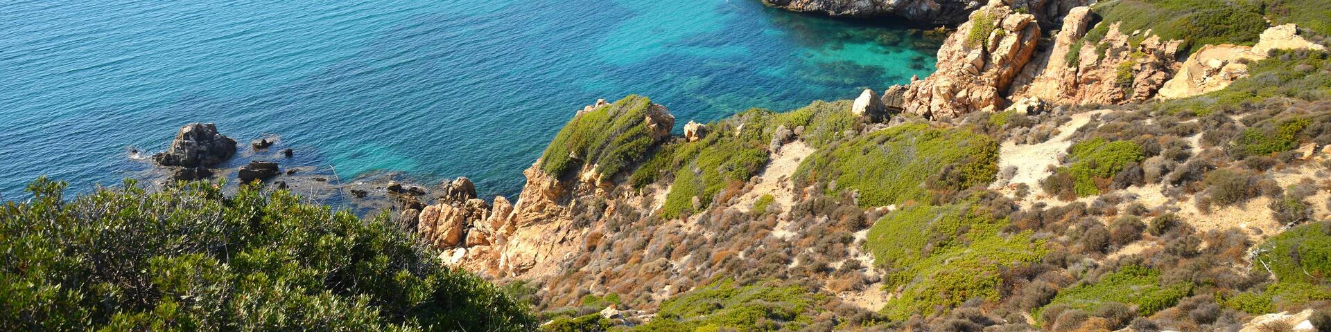 A coastal landscape with rocky terrain and clear blue waters.