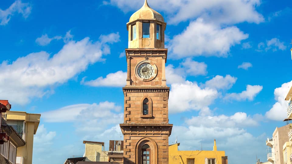 A historic clock tower with a dome, set against a blue sky with clouds.