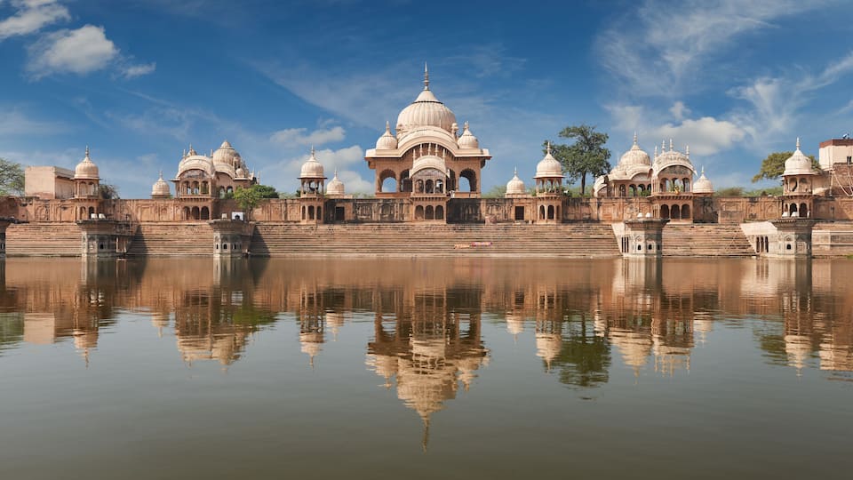 A historic building with multiple domes and arches, reflecting in a calm body of water.