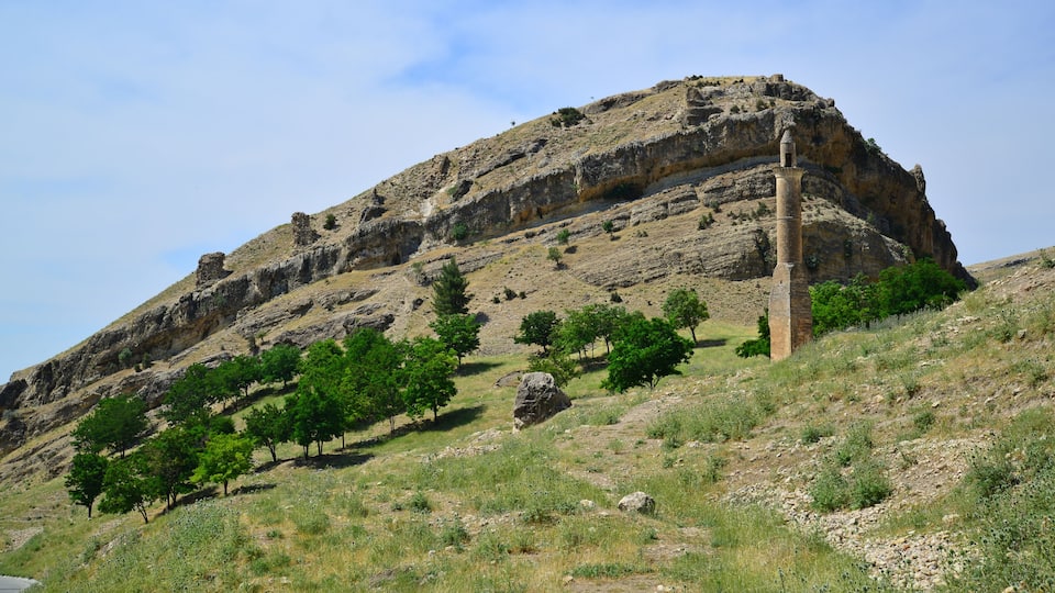 A rocky hill with a tall, narrow tower.