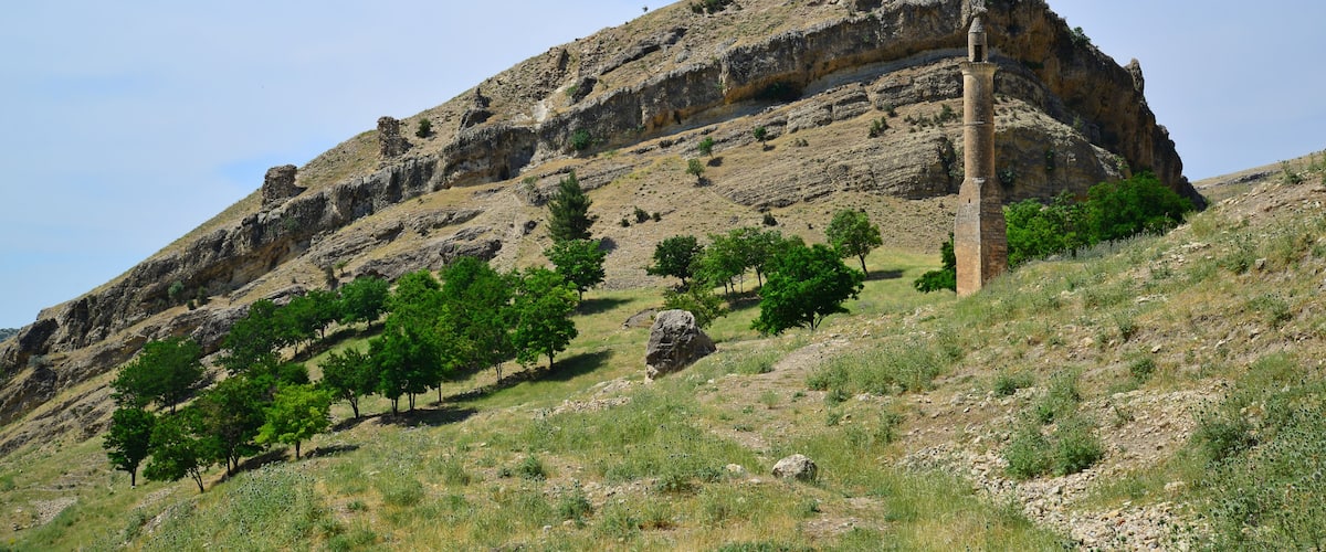 A rocky hill with a tall, narrow tower.