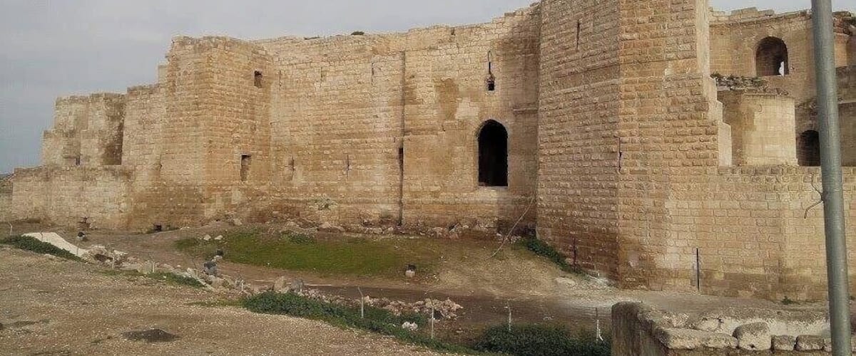 A large, ancient stone fortress with multiple arched doorways and a central courtyard.
