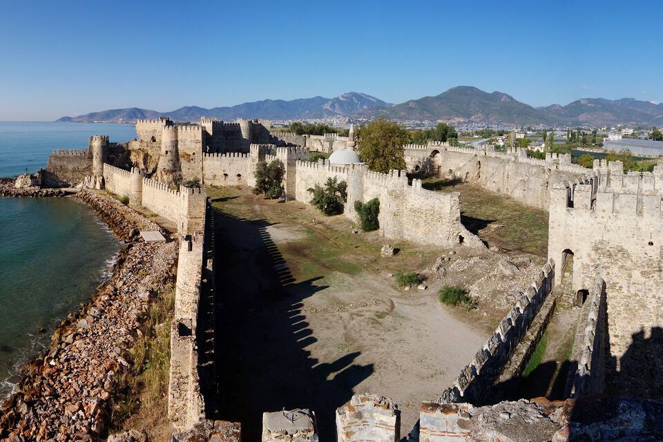 A coastal fortification with a clear view of the sea and mountains in the background.