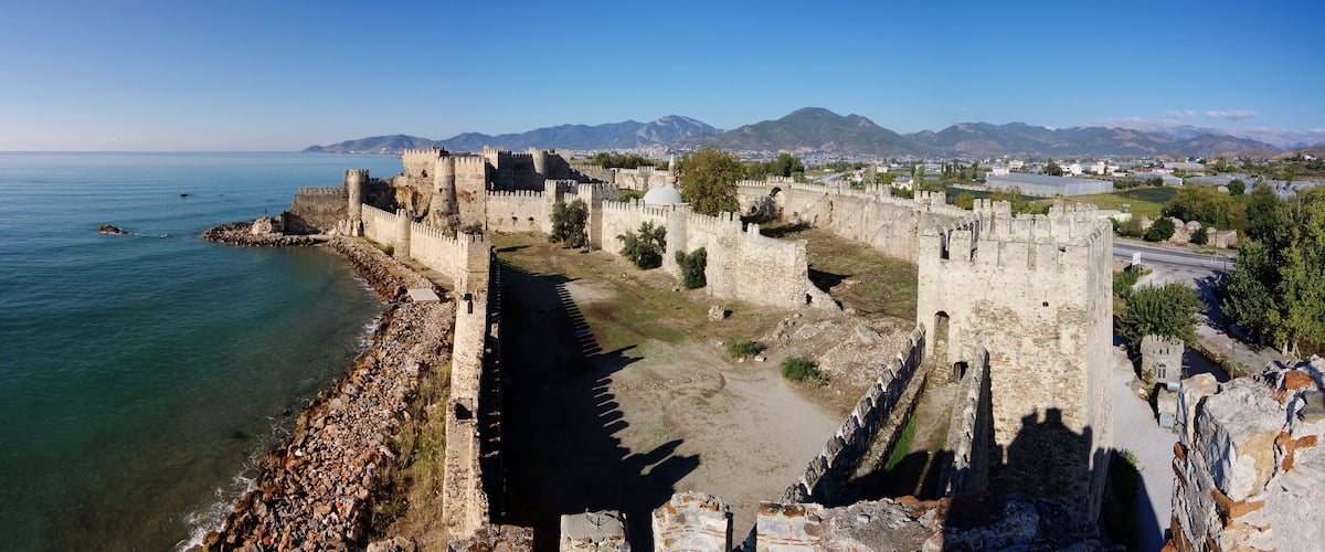 A coastal fortification with a clear view of the sea and mountains in the background.