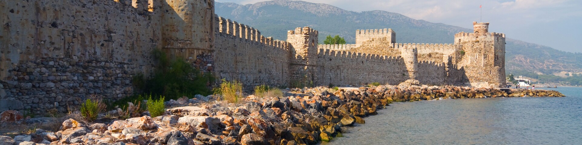 A historic stone wall with towers along a riverbank.