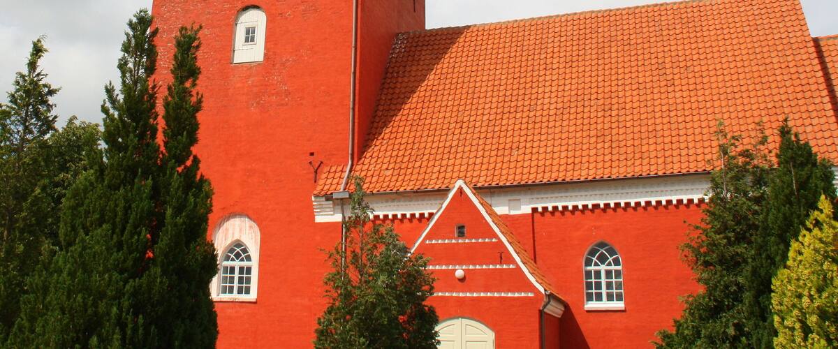 A red brick church with a tower and a red-tiled roof.