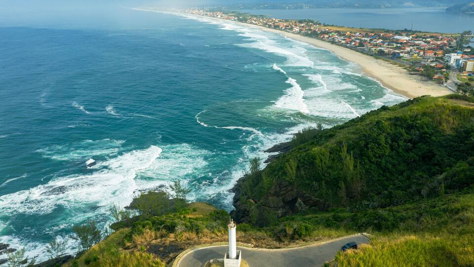 A coastal town with a lighthouse, beach, and ocean waves.
