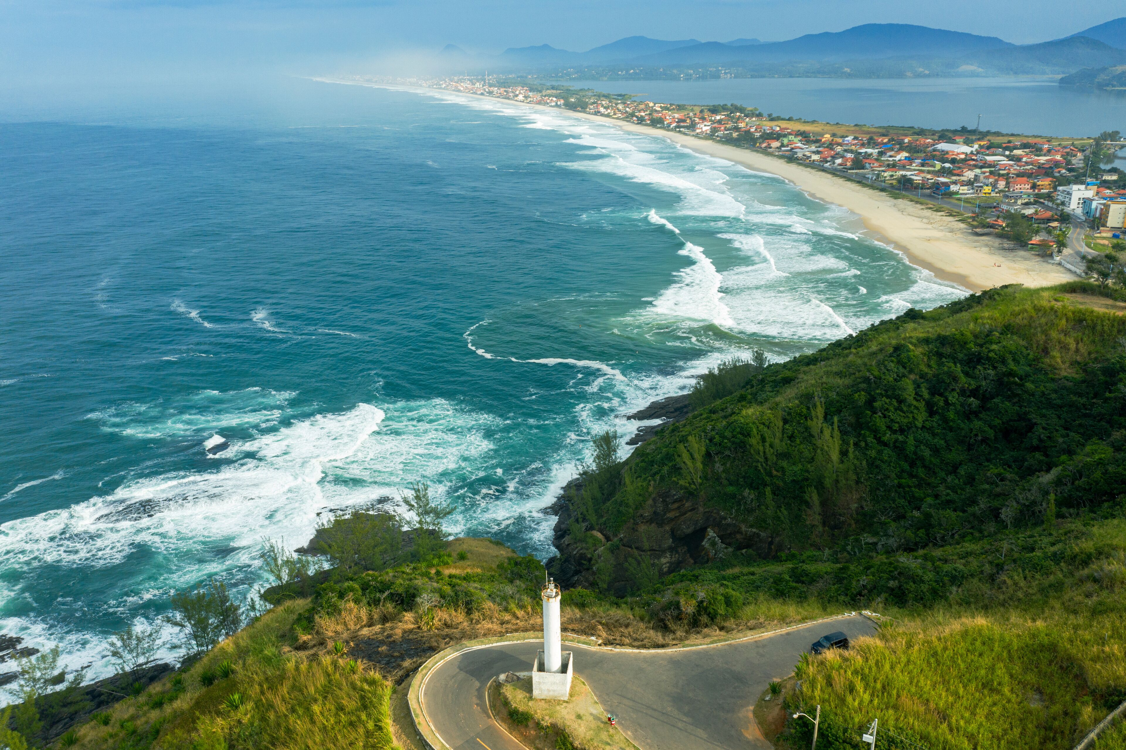 A coastal town with a lighthouse, beach, and ocean waves.