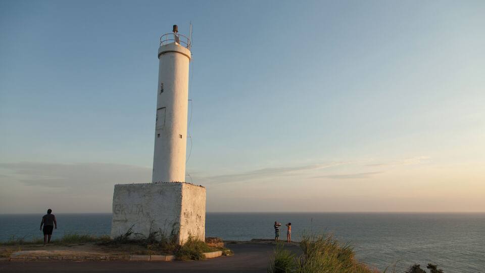 A white lighthouse by the sea with a clear sky.