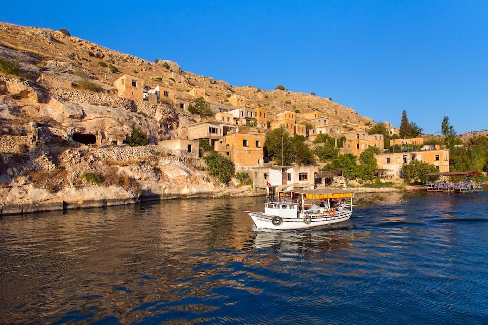 A boat on a river with a hillside settlement in the background.