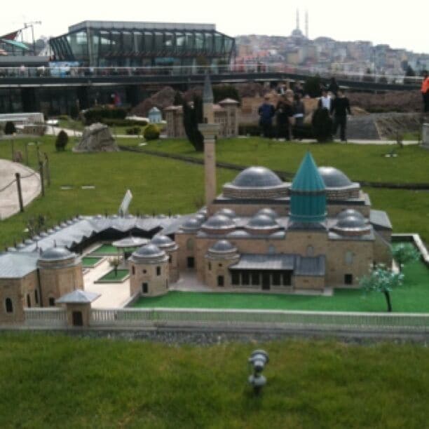 A model of a historical building with multiple domes and a central dome, surrounded by a green lawn and a fence.
