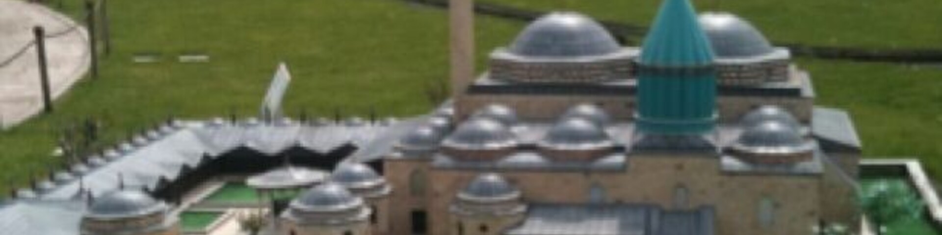 A model of a historical building with multiple domes and a central dome, surrounded by a green lawn and a fence.