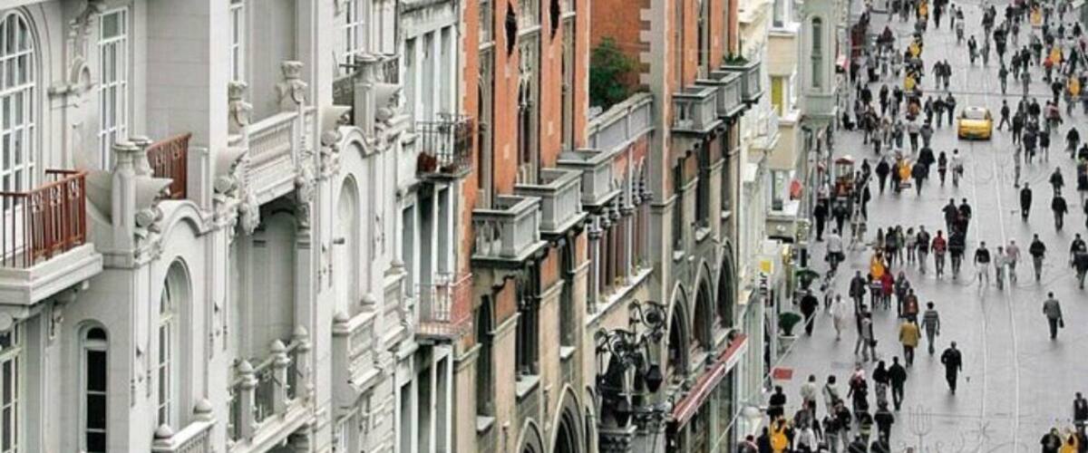 A bustling urban street lined with historic buildings, a tram, and pedestrians.