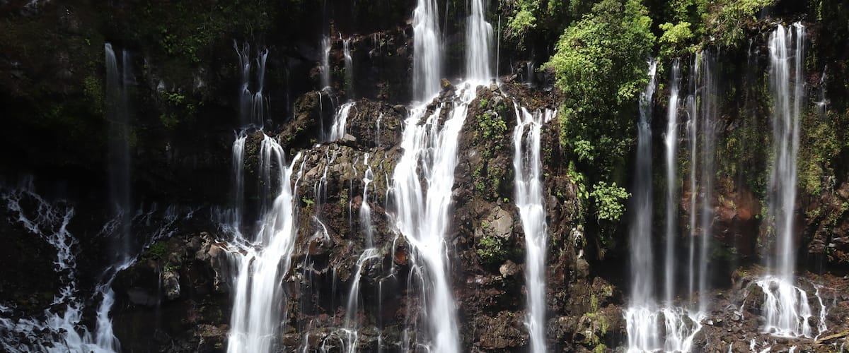 A multi-tiered waterfall cascading over rocks into a pool.
