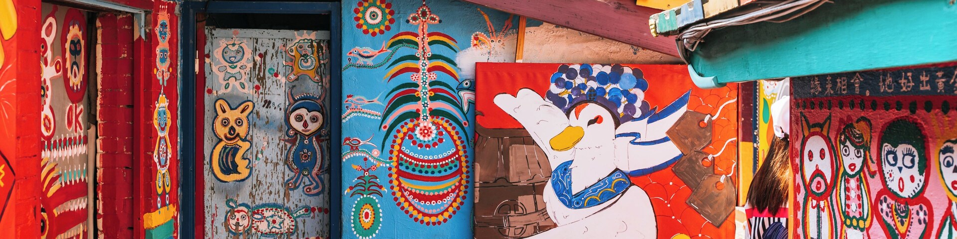 Murais coloridos na fachada de um edifício, incluindo uma grande representação de um pato e diversos padrões abstratos.