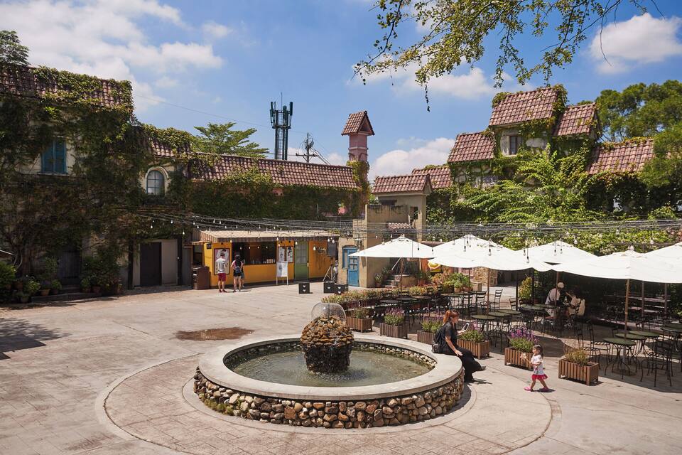 A courtyard with a fountain, outdoor seating, and ivy-covered buildings.