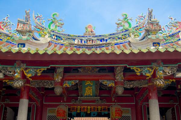 Un temple chinois traditionnel, orné de décorations complexes représentant des dragons et doté de piliers rouges.