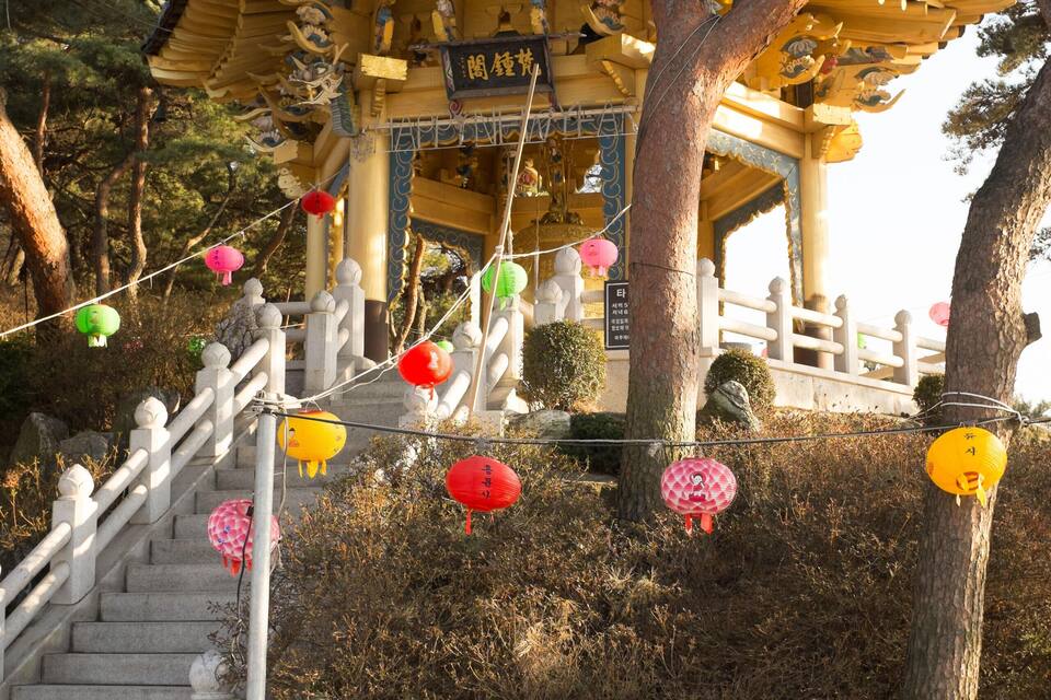 A traditional temple with a golden roof, stone stairs, and lanterns.