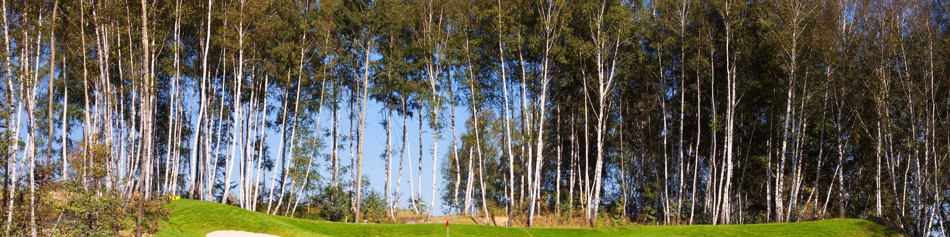 Golf course in autumn, grass field and lake