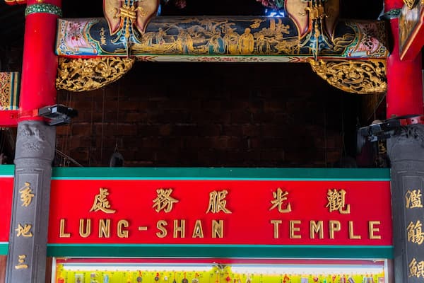 The entrance of Lung-Shan Temple with red and gold decorations and Chinese characters.