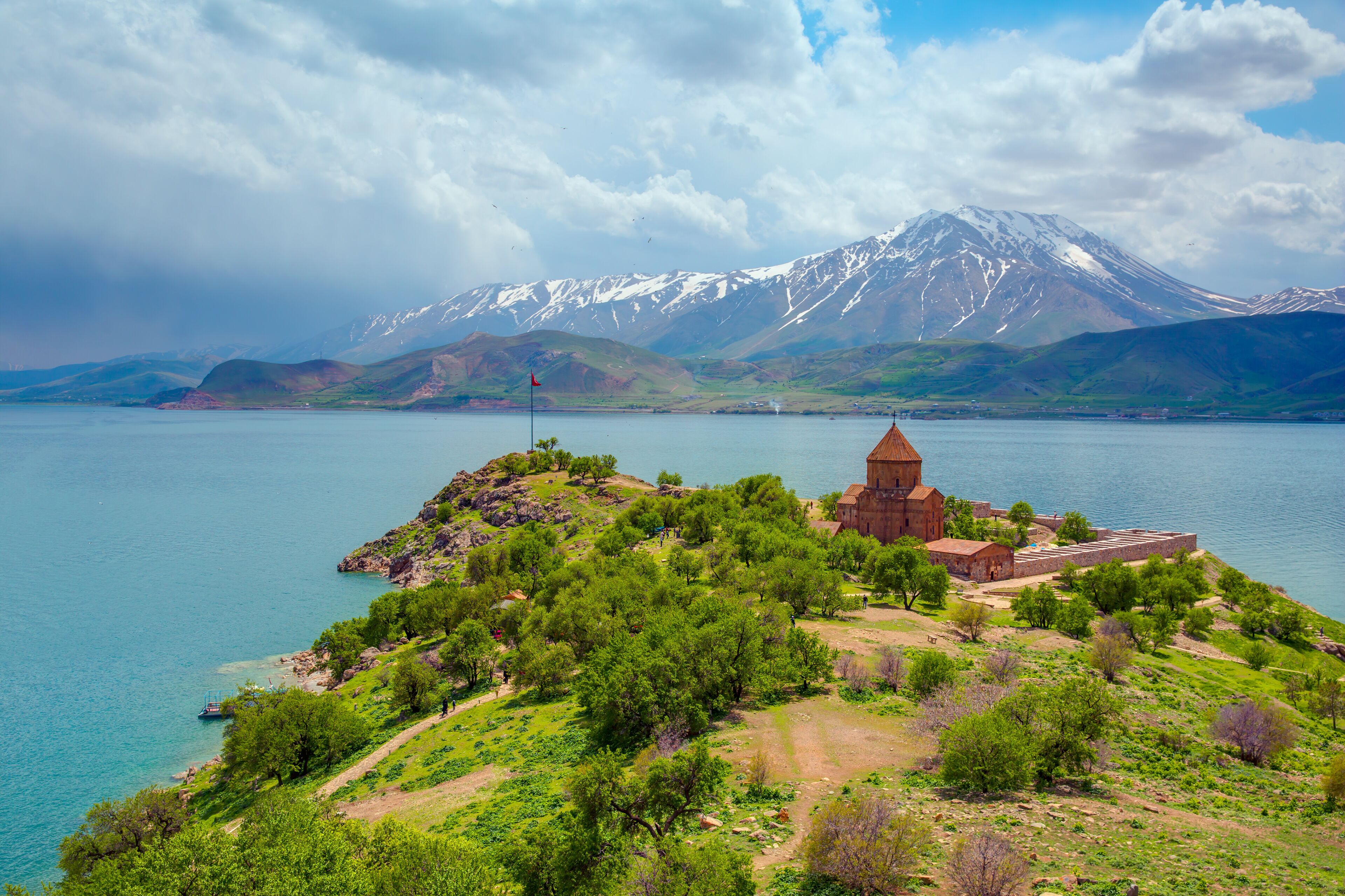A coastal landscape with a church, a mountain range, and a body of water.
