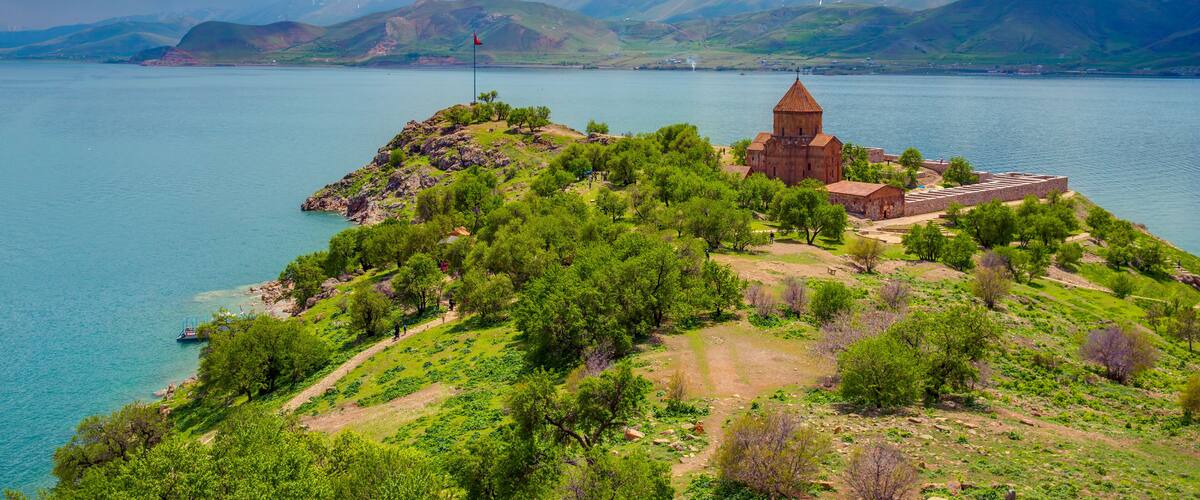 A coastal landscape with a church, a mountain range, and a body of water.