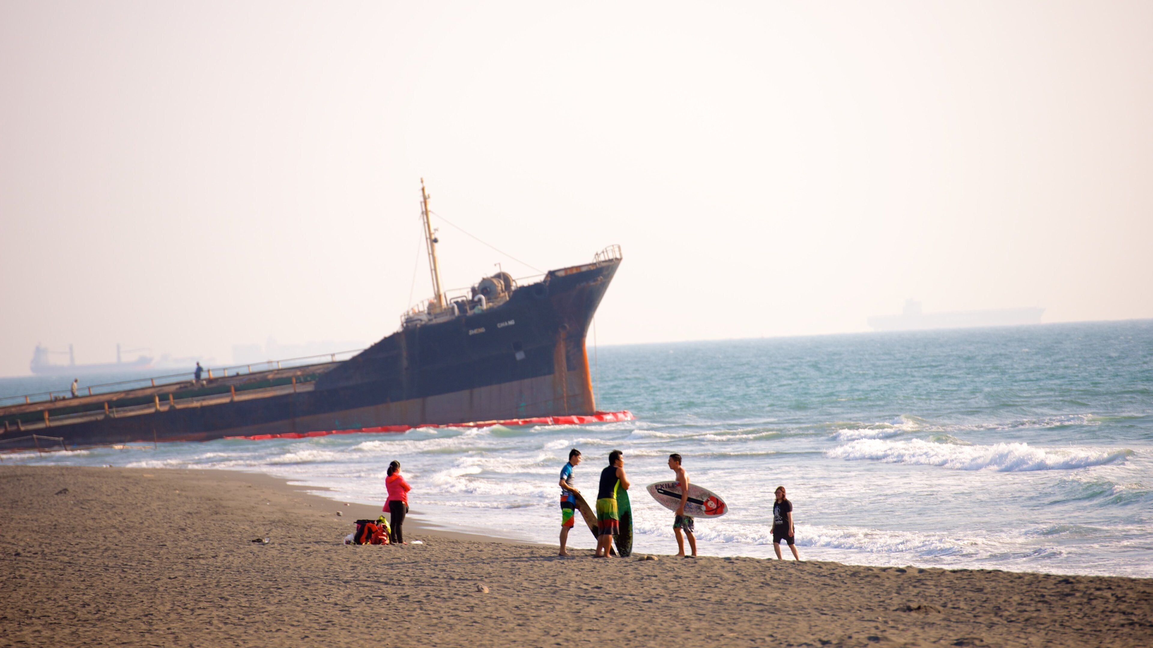 Cijin Seaside Park featuring a beach as well as a small group of people