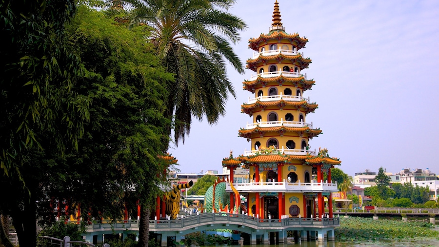 Una pagoda de varios niveles con arquitectura tradicional, rodeada de abundante vegetación y un pequeño puente sobre el agua.