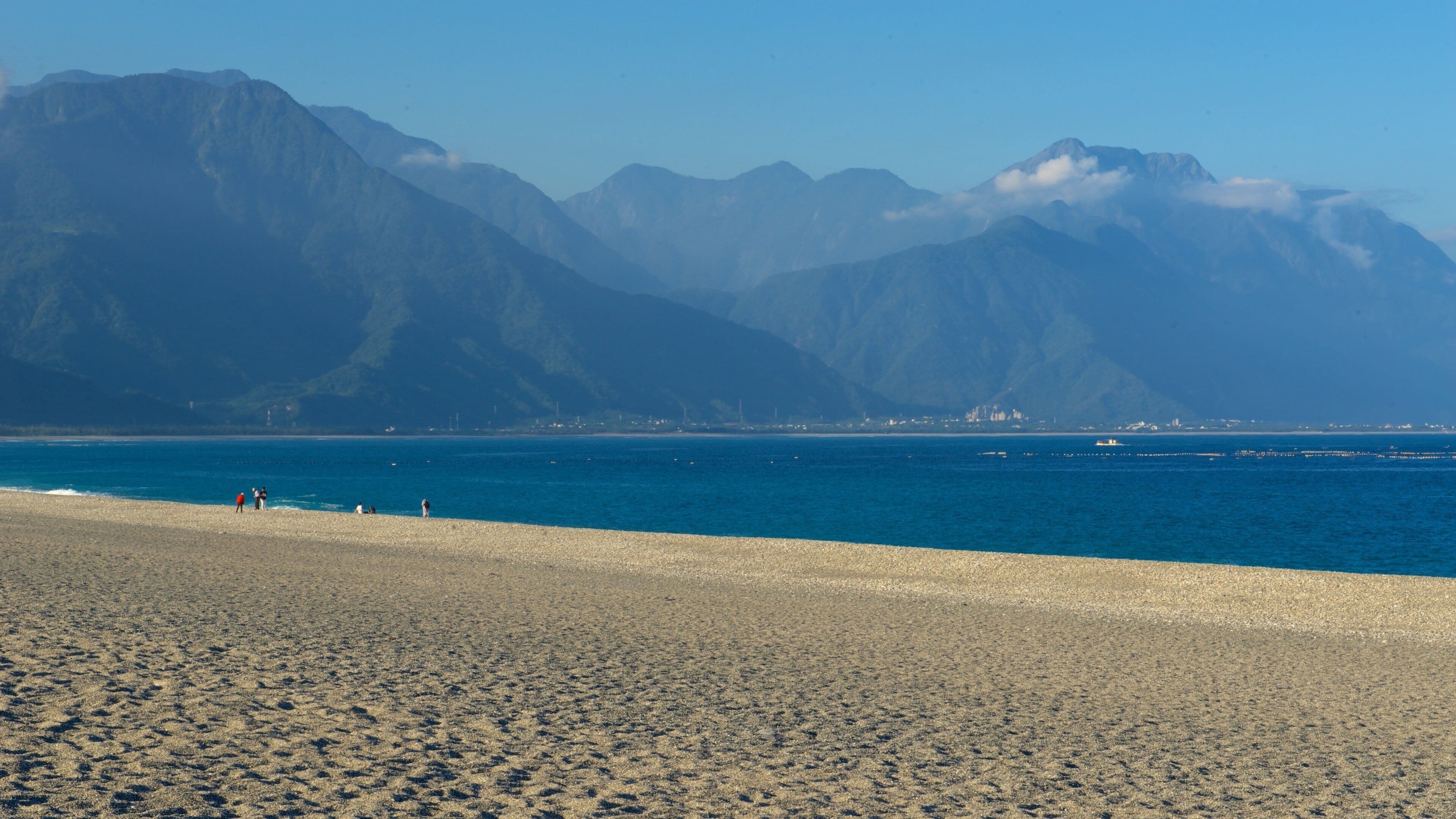 Uma praia com montanhas ao fundo.