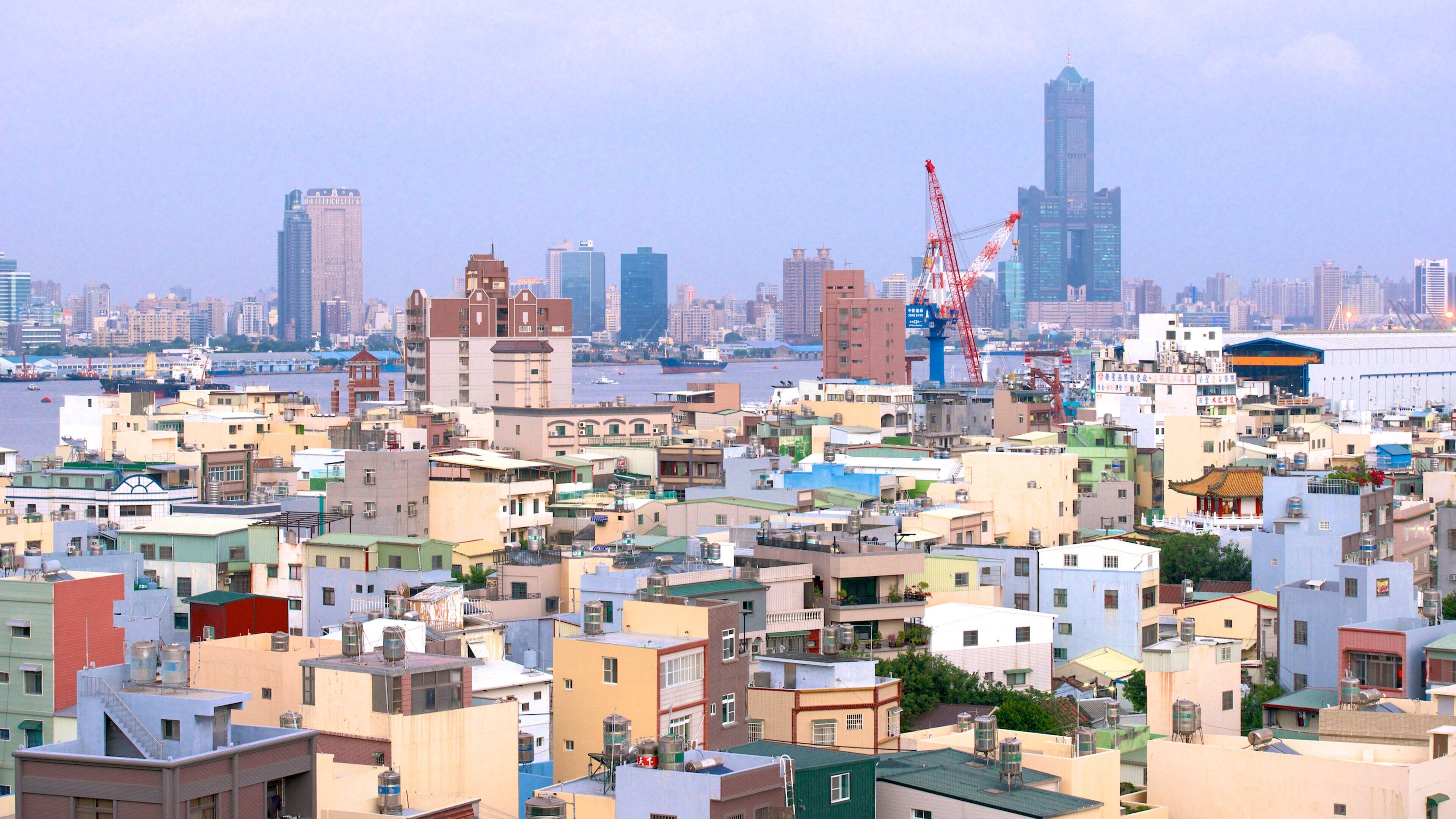 A densely packed urban area with a mix of residential and commercial buildings, a river in the background, and several cranes indicating construction activity.