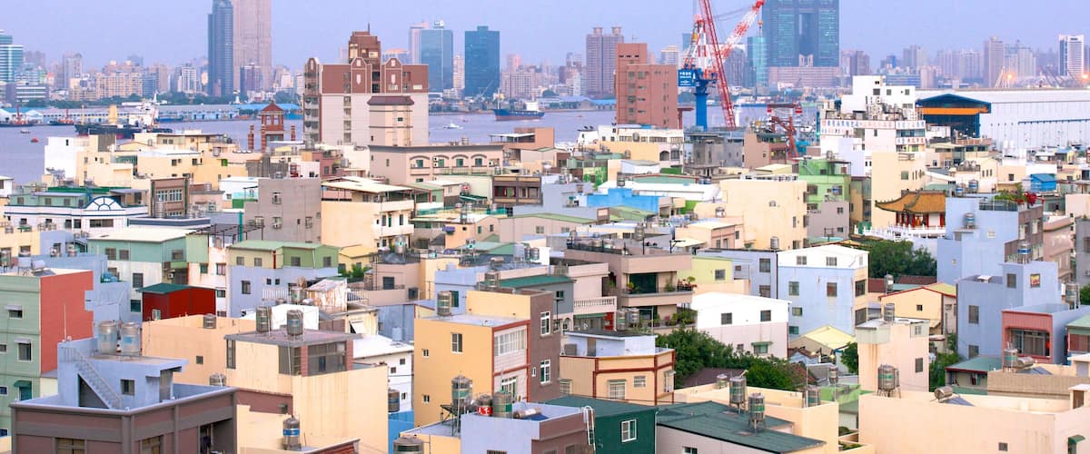 A densely packed urban area with a mix of residential and commercial buildings, a river in the background, and several cranes indicating construction activity.