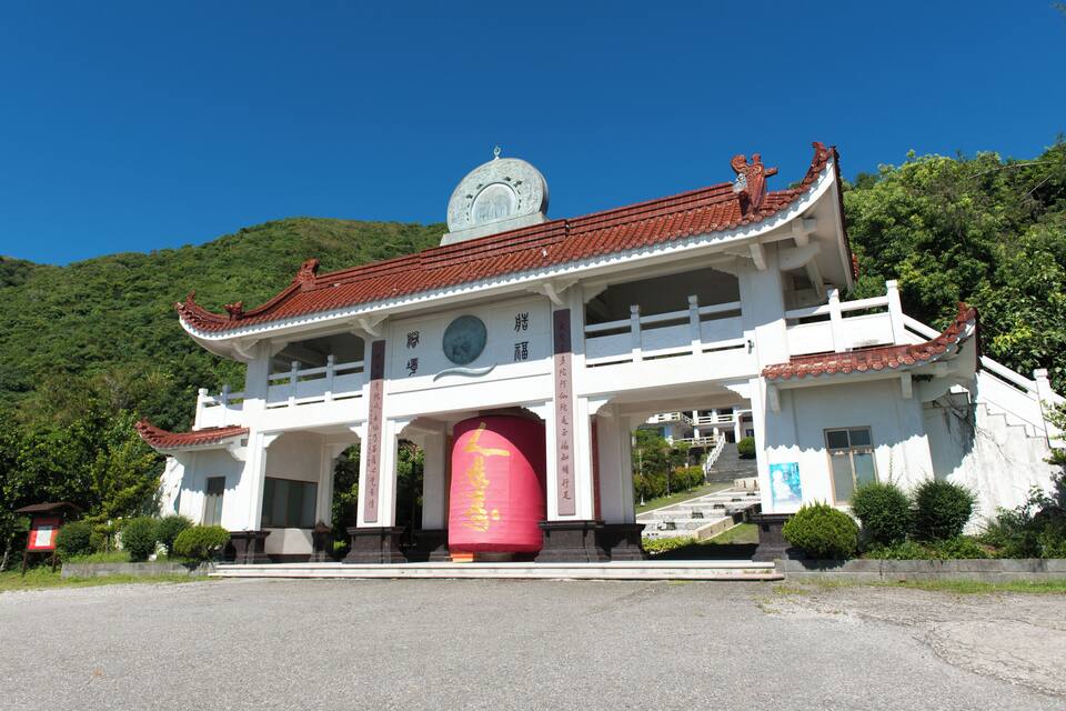 Um edifício tradicional chinês com telhado de telhas vermelhas, um pilar vermelho grande e um campanário.