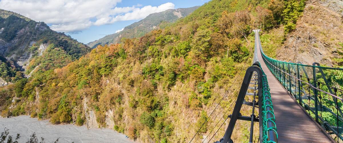 A suspension bridge in a mountainous area with autumn foliage.