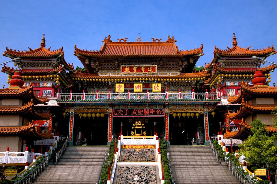A traditional Chinese temple with ornate architecture, a large central gate, and a statue of a deity at the entrance.