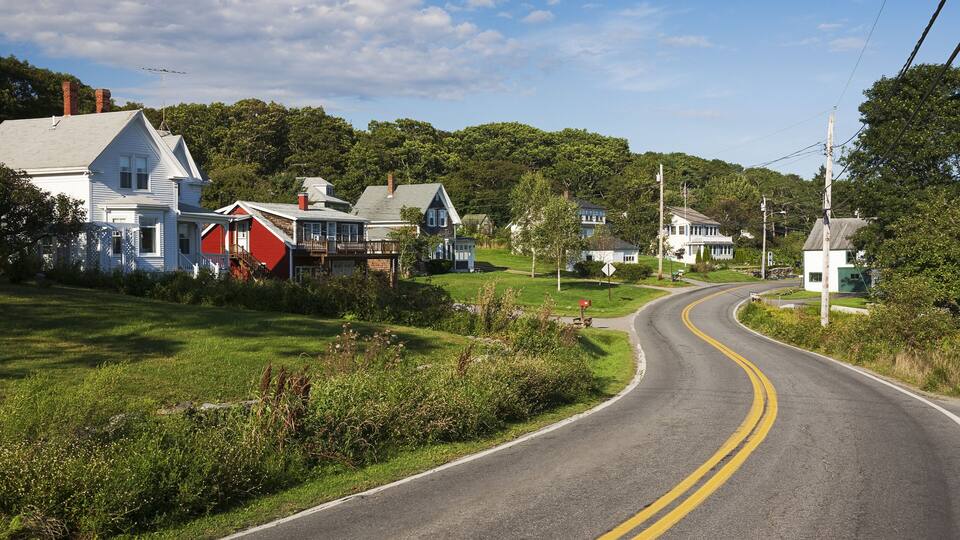 A rural road winding through a small town with houses on both sides.