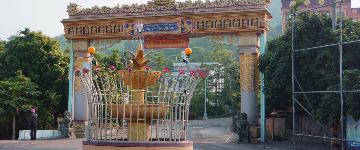 A traditional gate with ornate decorations and a central fountain with flowers.